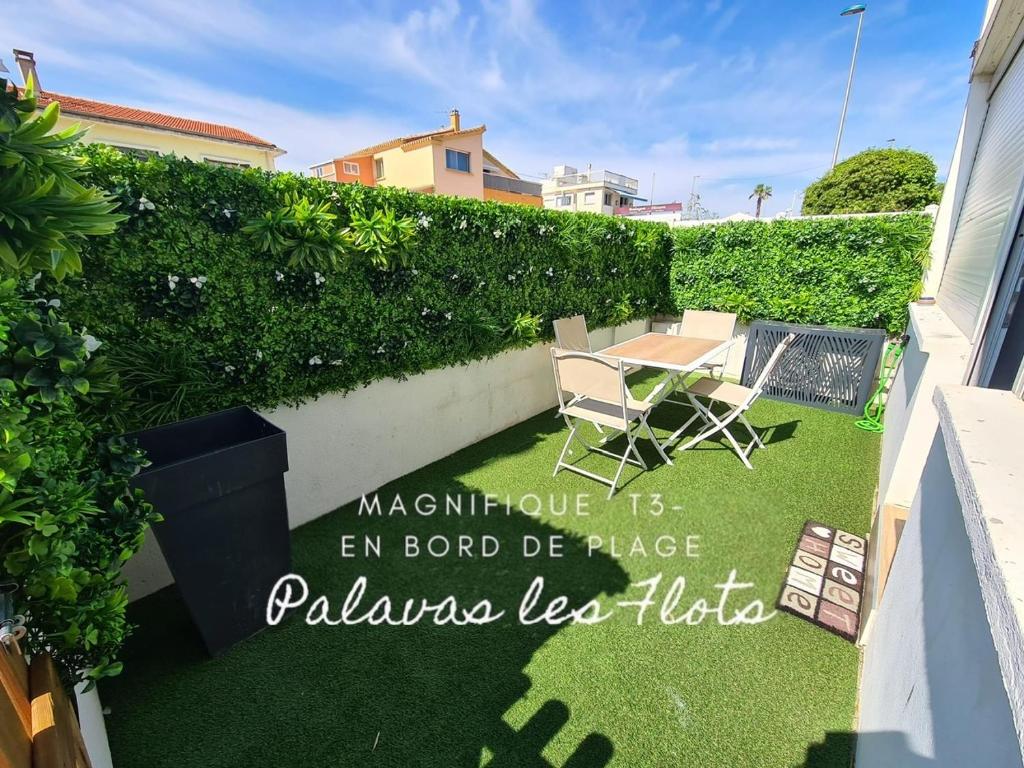 une petite arrière-cour avec une pelouse dotée d'une table et de chaises dans l'établissement Charmant appartement à 50 m de la plage, à Palavas-les-Flots