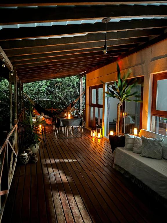 a wooden deck with a couch and a table at Casa Bouganville in Monte das Gameleiras