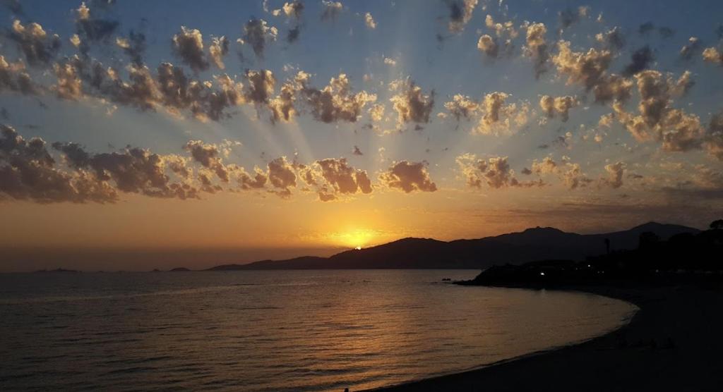 un coucher de soleil sur l'eau avec des nuages dans l'établissement T2 Azur - Plage & commerces à 200m- Barbecue - Parking - Wifi, à Albitreccia