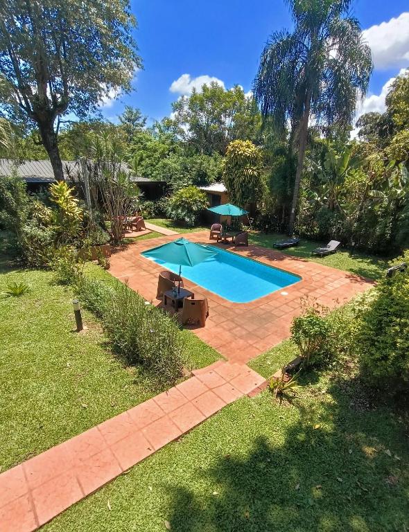 un patio trasero con una piscina con sombrillas en El Descanso Iguazú by DOT Cabana, en Puerto Iguazú