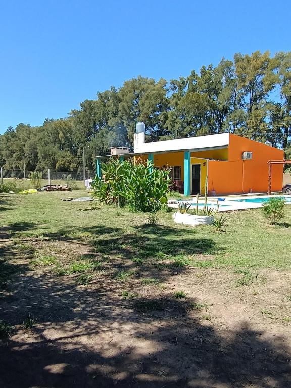 a small orange house in a field with trees at Casa Quinta San Pedro in San Pedro