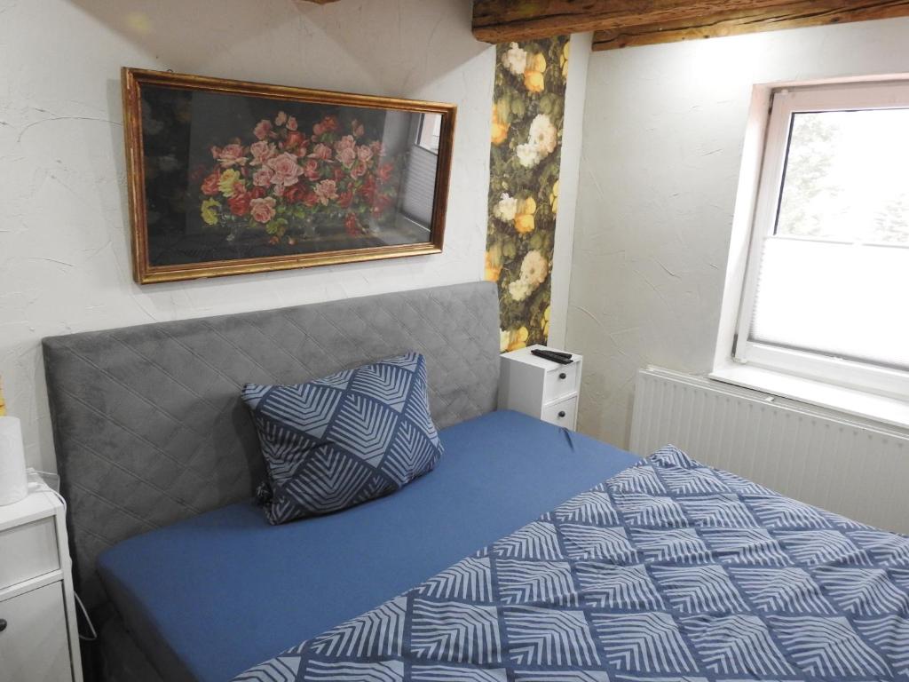 a bedroom with a blue bed with a picture on the wall at Alter Wirt in Steckelsdorf