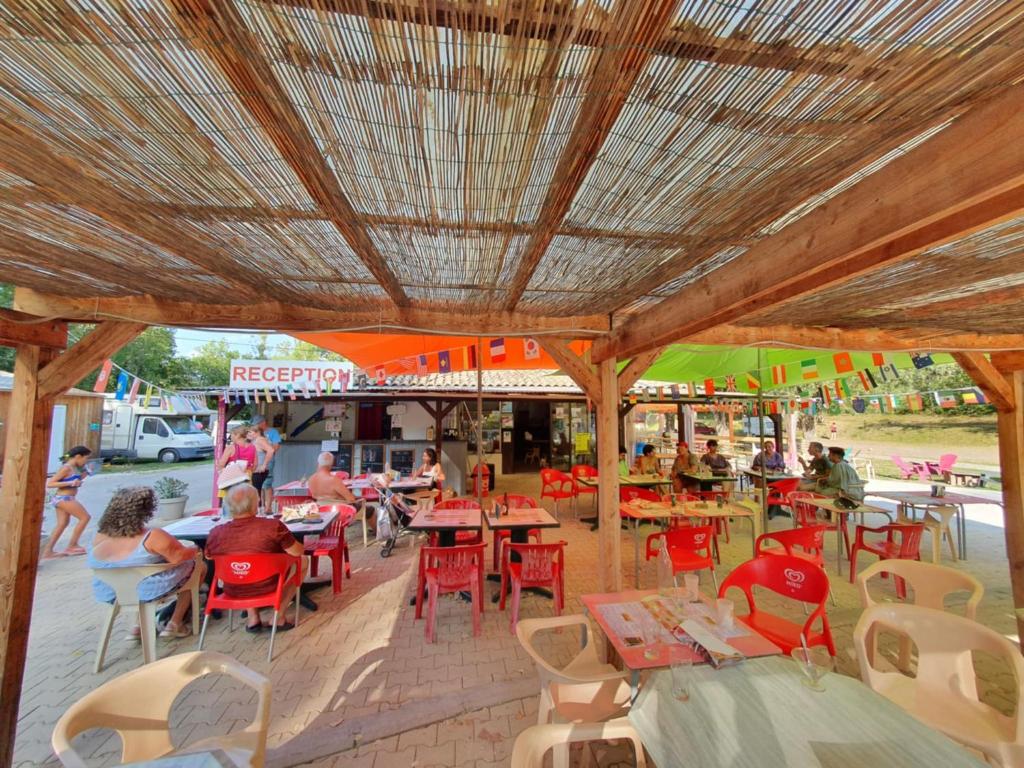 un groupe de personnes assises à des tables dans un restaurant dans l'établissement Mobil home 6 personnes, à Barrême