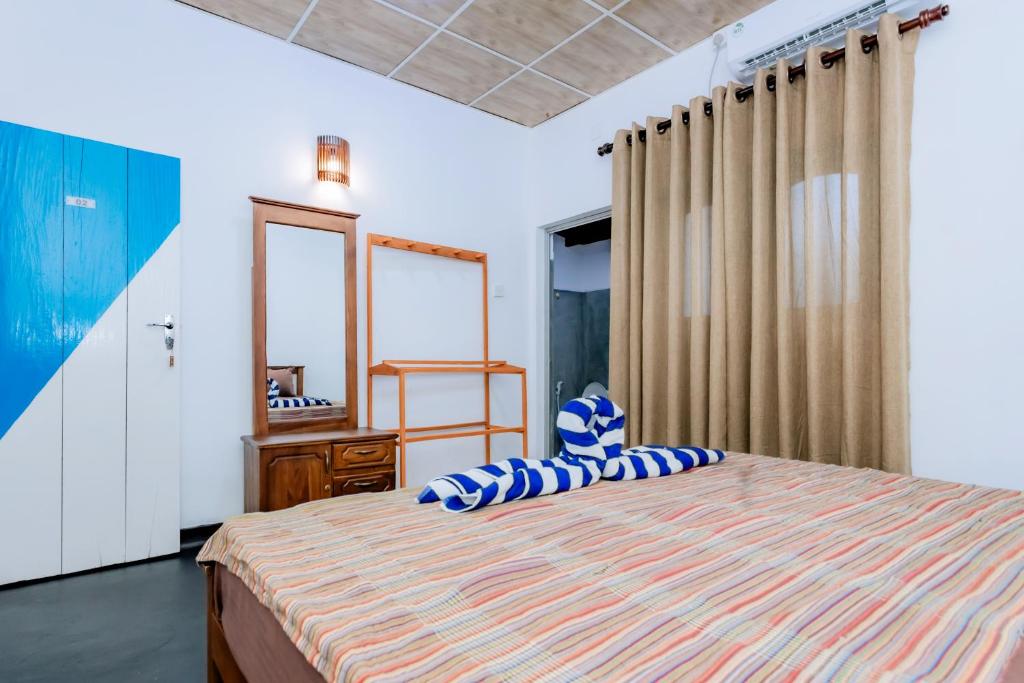 マータラにあるMadiha Ceylon Hotelのベッドルーム(青い枕と鏡付きのベッド1台付)