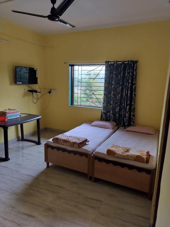 阿利鲍格Gulmohar Cottages - Home Stay in Alibag的一间卧室配有一张床、一张桌子和一个窗户。