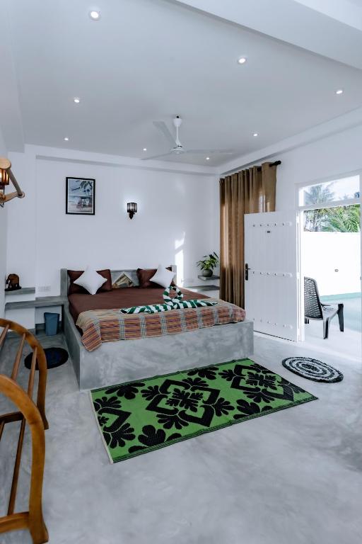 a bedroom with a bed and a green rug at Madiha Ceylon Hotel in Matara