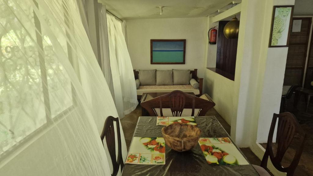 a dining room with a table and a couch at Boma Banda Diani - Kaskazi Cottage in Diani Beach