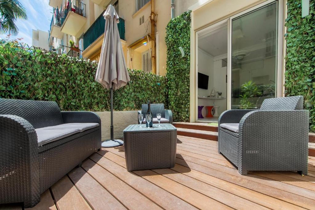 un patio avec deux chaises et un parasol dans l'établissement MUSICIENS Joli DUPLEX 2 Chambres Garage privatif et Terrasse, à Nice