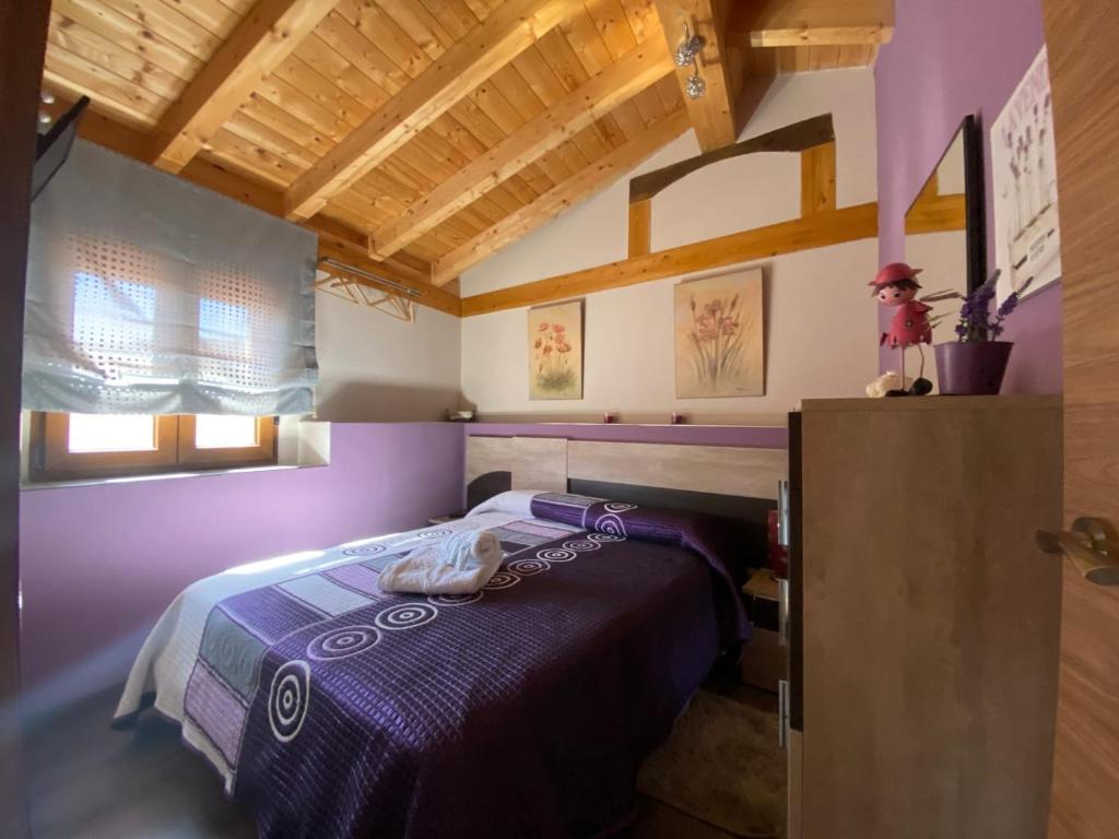 a bedroom with a purple bed and a wooden ceiling at Casa Rural María y Daniel in Castrillo de Duero
