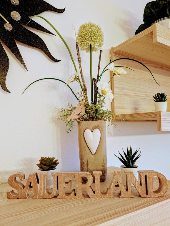 a wooden sign with a vase with a plant at Ferienwohnung Jansen in Kirchhundem