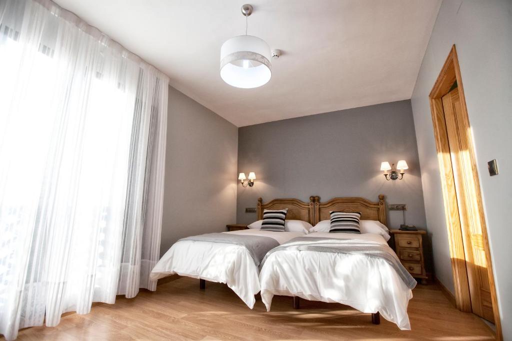 Un dormitorio con dos camas y una gran ventana. en Hotel Santa Cruz, en Cangas de Onís