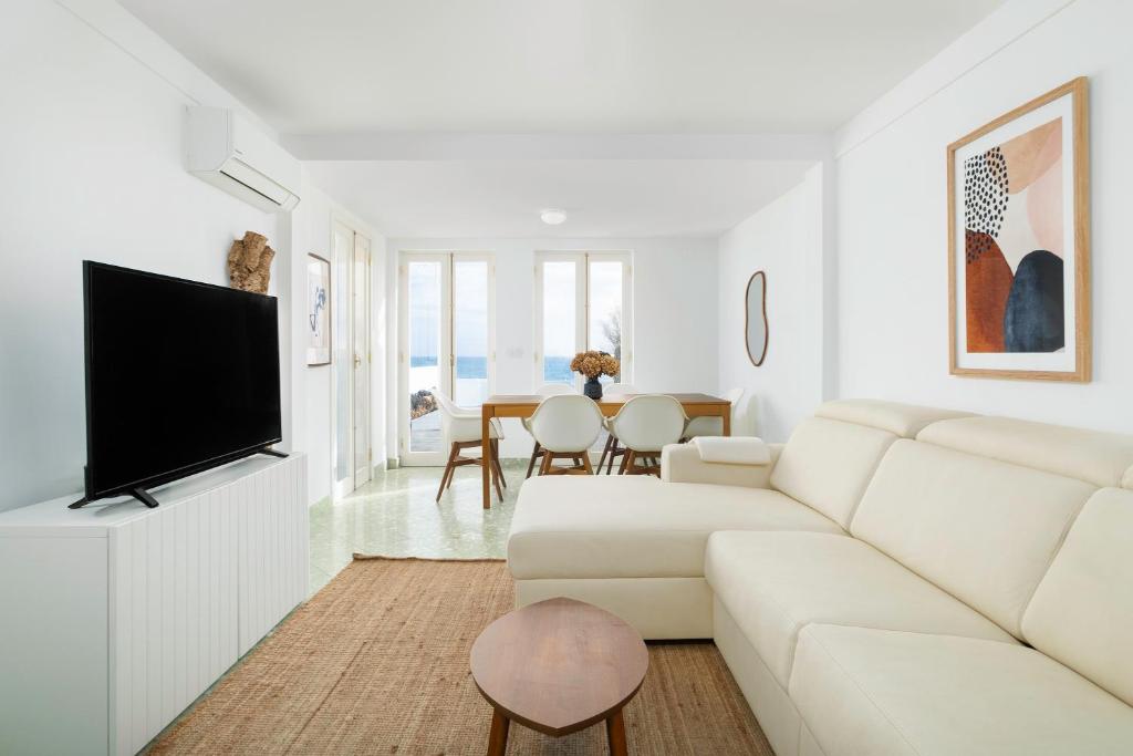 a white living room with a white couch and a tv at Ocean View Retreat 2 - Sea View with Jacuzzi in São Roque