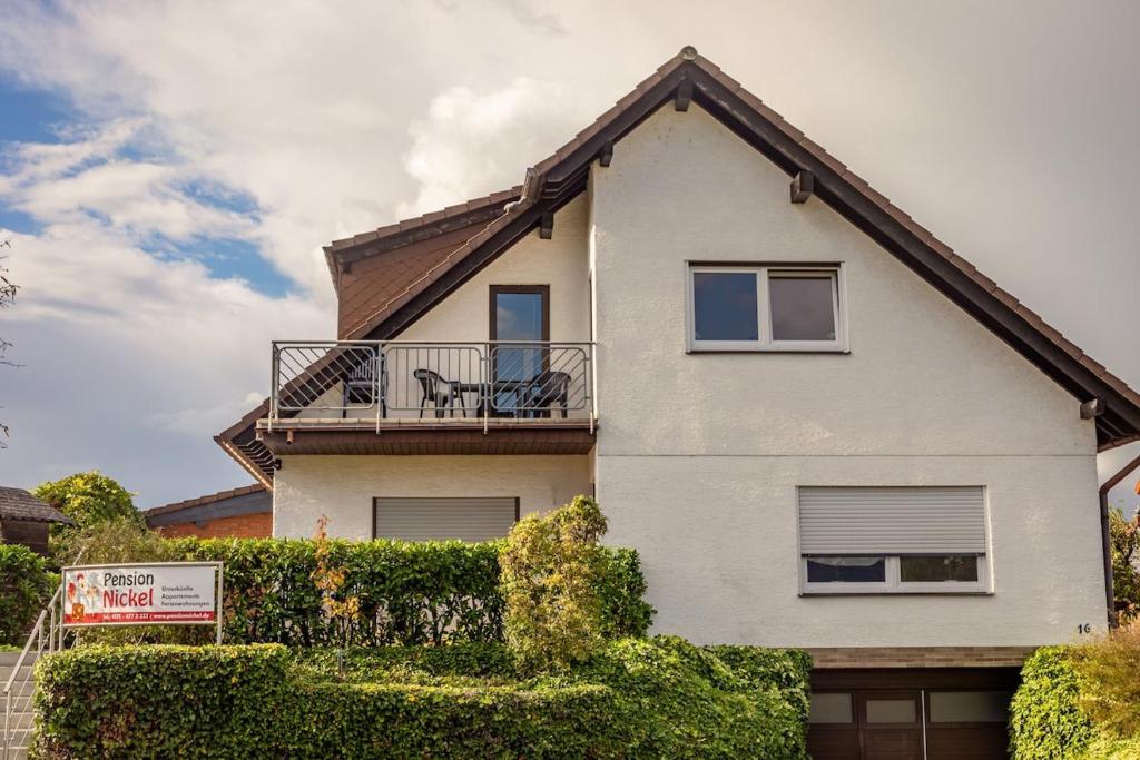 a white house with a balcony on top of it at Pension Nickel Ferienwohnung DG Am Holzlachgraben in Alsbach-Hähnlein