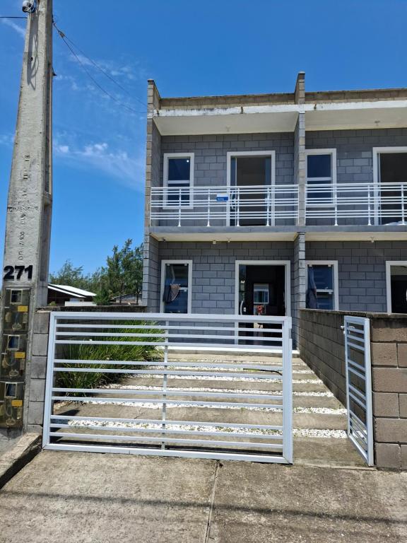 una casa con un cancello bianco davanti di S1 - Residencial Soulmar Balneário Gaivota - SC - Village Dunas Norte - 1,5 quadra do mar a Balneário Gaivotas