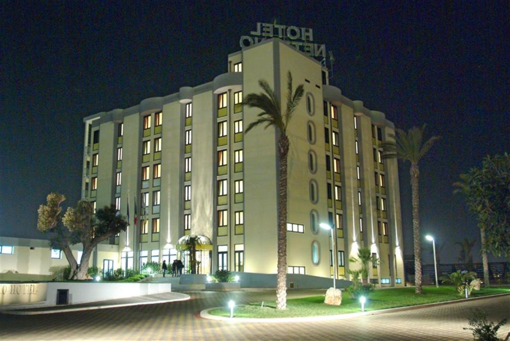a large building with a palm tree in front of it at Best Western Hotel Nettuno in Brindisi