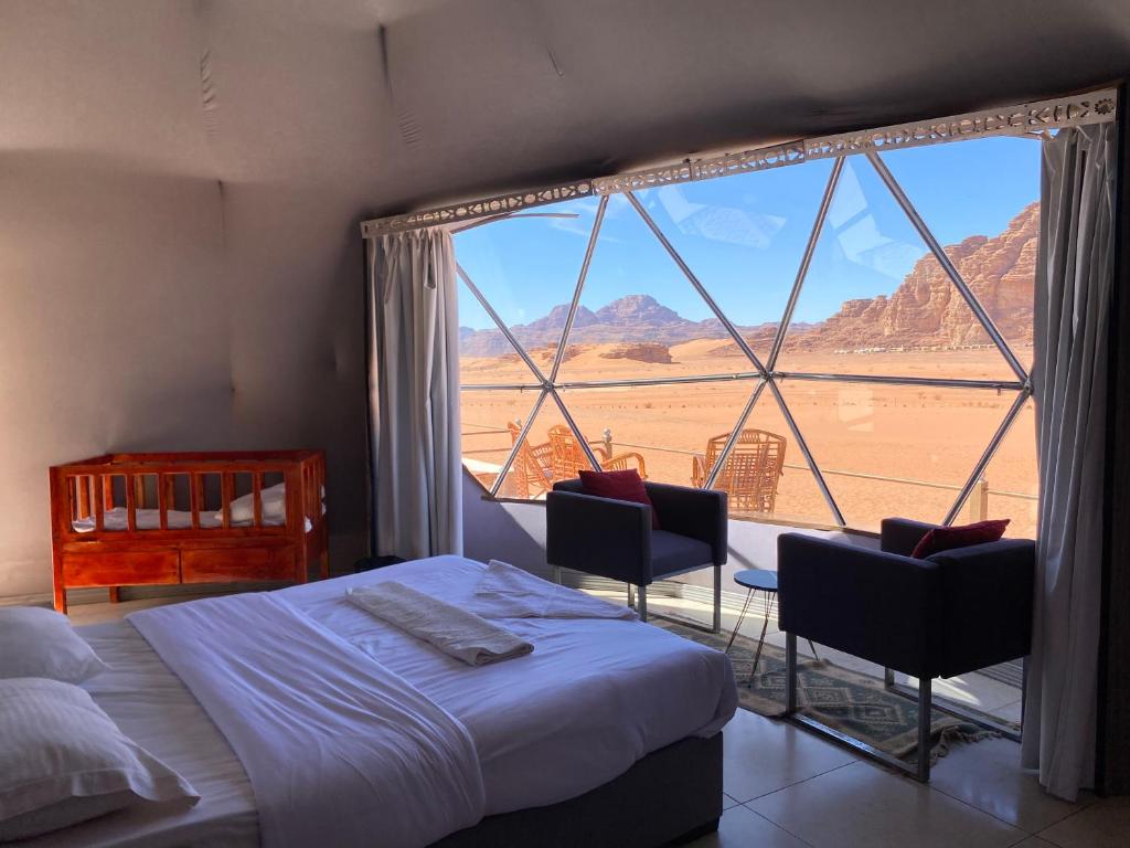 a bedroom with a bed and a large window at Katrina Rum camp in Wadi Rum