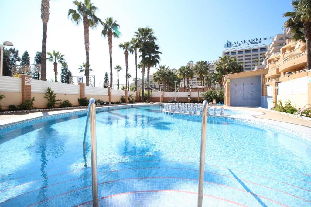 a large swimming pool with palm trees and a building at Apartamento Maru's in Oropesa del Mar