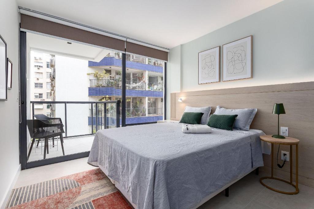 a bedroom with a large bed and a balcony at Apê Aconchegante | Piscina, Sauna e Metrô 350m in Rio de Janeiro