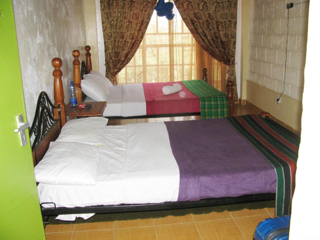 a bedroom with two beds and a window at Lulu's Guest House in Nairobi