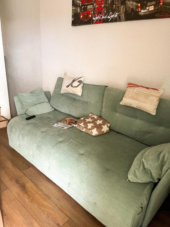 - un canapé vert dans le salon dans l'établissement Charmant duplex à Font-Romeu Odeillo Via, à Font-Romeu-Odeillo-Via