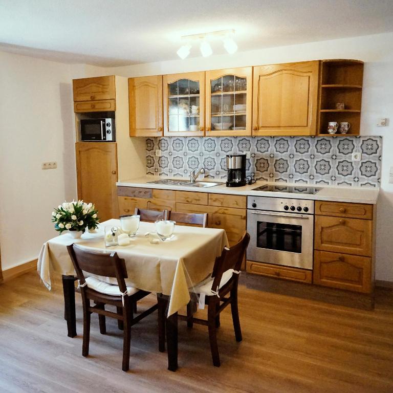 a kitchen with a table with chairs and a kitchen with a stove at Ferienhof am Ipf in Bopfingen