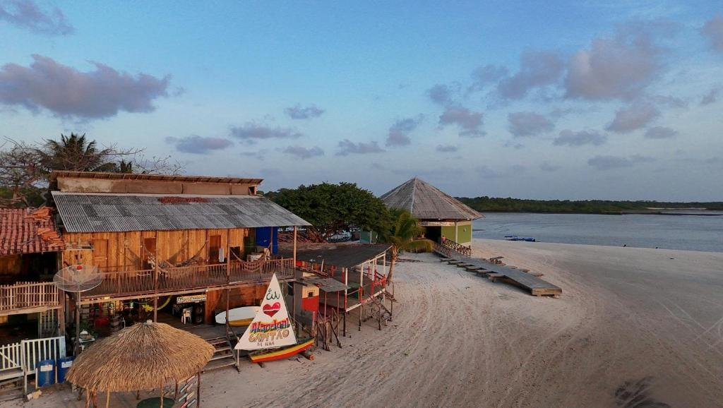 a beach with a building and a boat on it at Hostel Capitão da Ilha in Algodoal