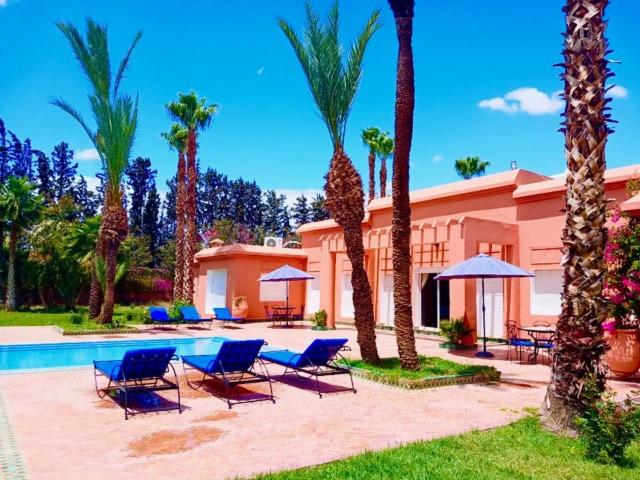 a resort with chairs and a pool and palm trees at Villa Rayan Marrakech secteur Palmeraie dans Propriété de 2 hectares avec jardin arbres fruitiers in Marrakesh