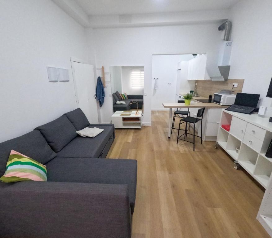 a living room with a gray couch and a kitchen at Anna Home in Telde