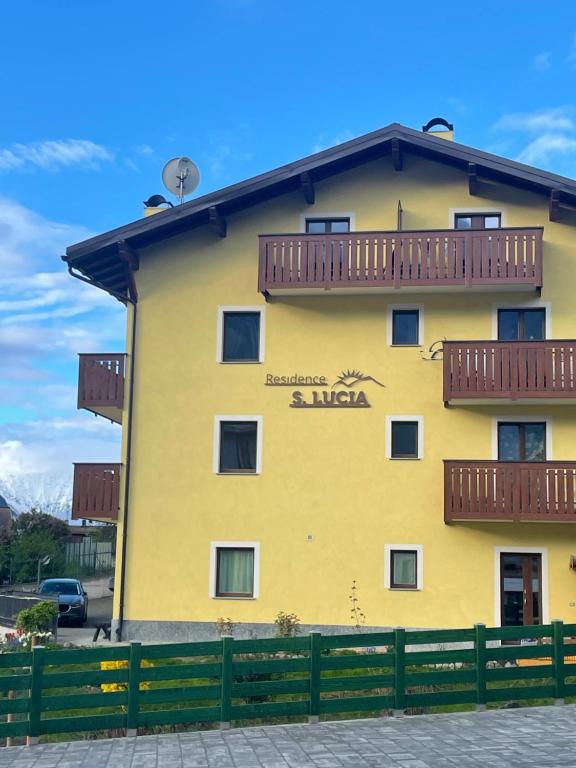 a yellow building with balconies on the side of it at Residence S Lucia - Appartamenti alle porte di Bormio in Valdisotto