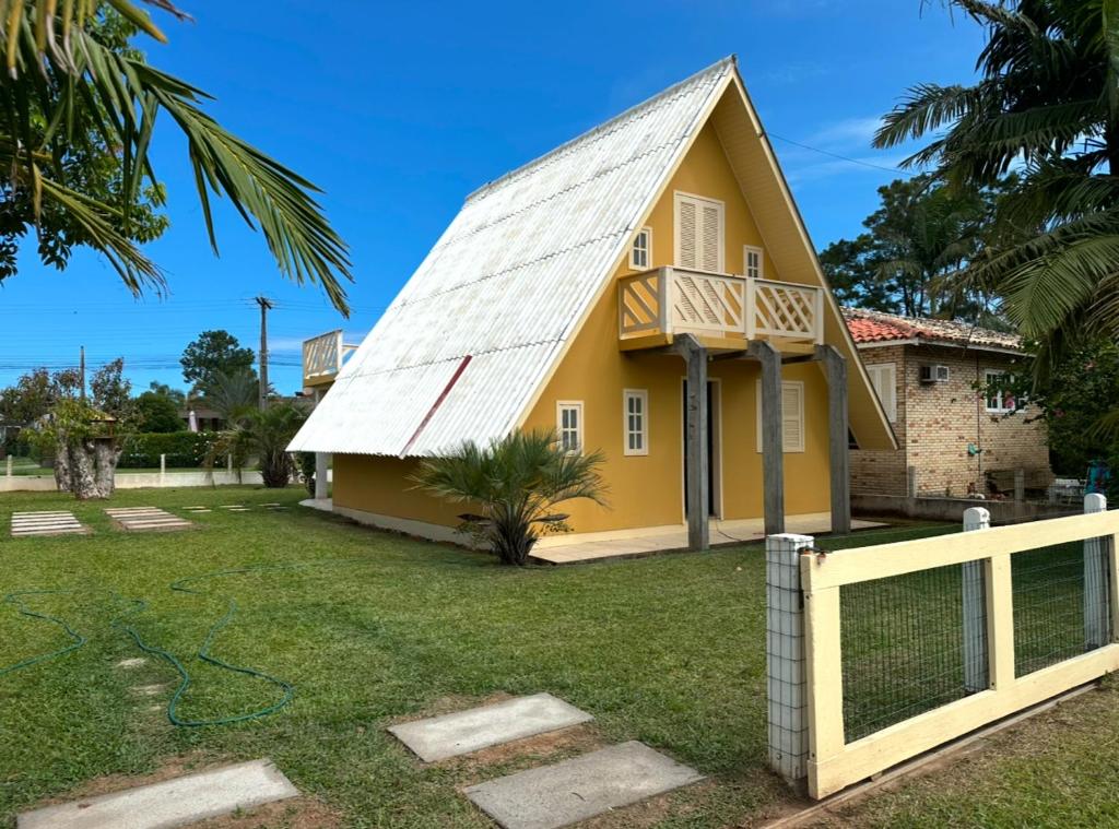 a yellow house with a metal roof at Chalé Condomínio Vila Suiça - Balneário Rincão in Vila Nova