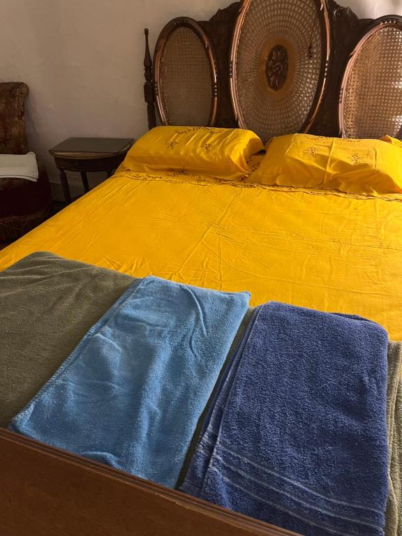 a yellow bed with blue sheets and yellow pillows at Pousada famíliar in São Gabriel