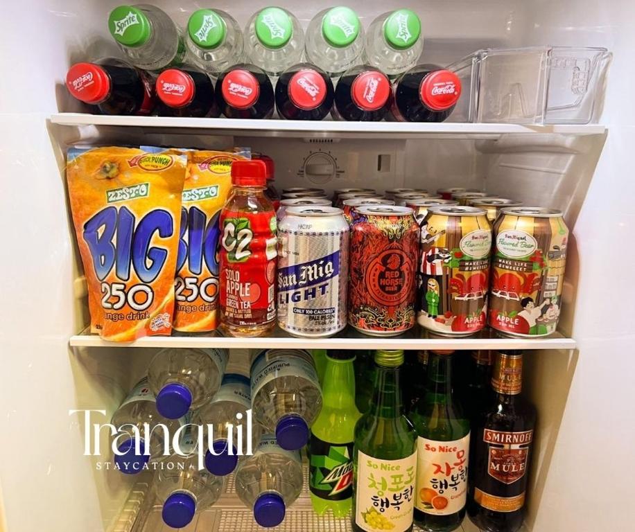 Un refrigerador lleno de muchas bebidas y refrescos. en Tranquil Staycation at Azure, en Manila