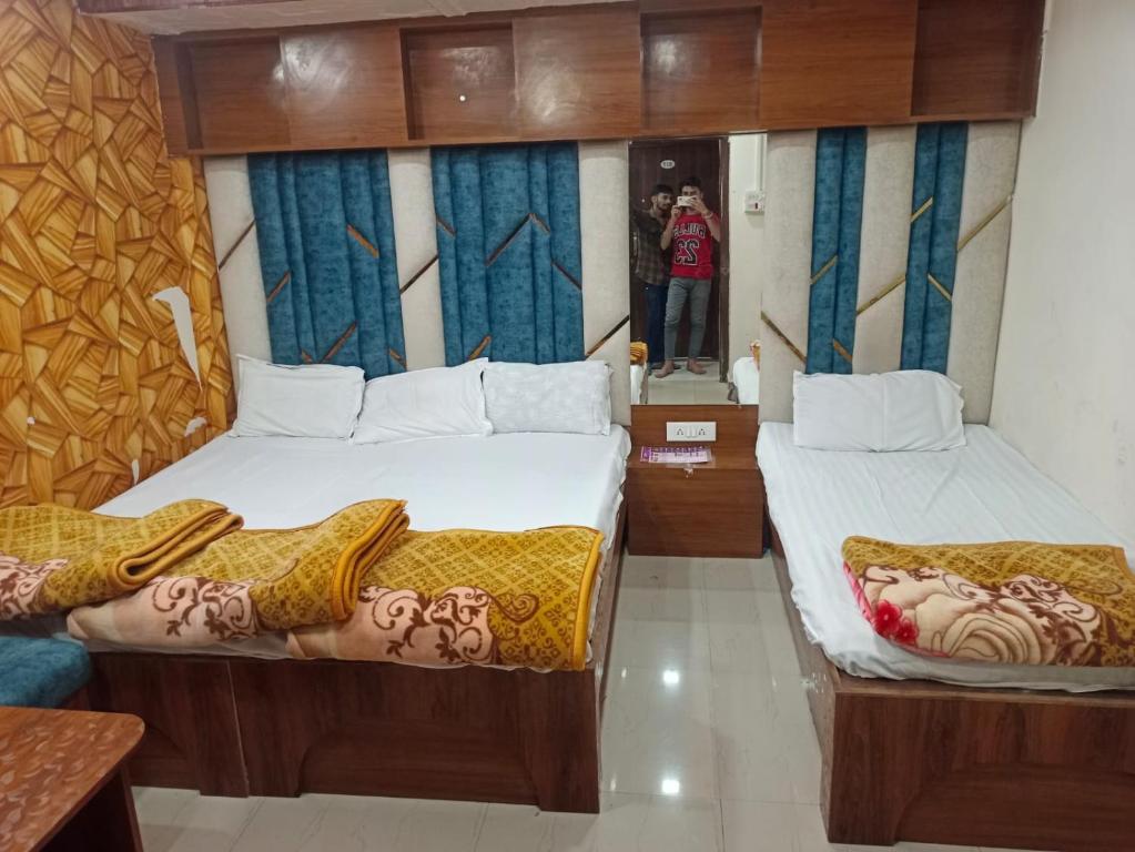 two beds in a room with a person taking a picture at Shree Sampatbai yatri ghar in Ujjain