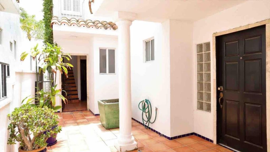a black door in a white house with plants at Tijuana Beach View & Patio in Tijuana