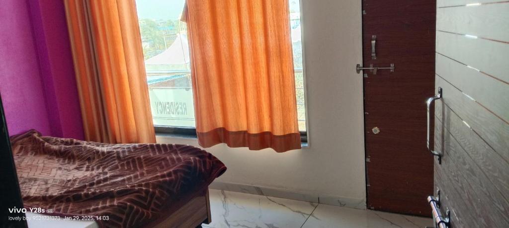 a bedroom with an orange curtain and a window at Ram karsan hotel in Khātu