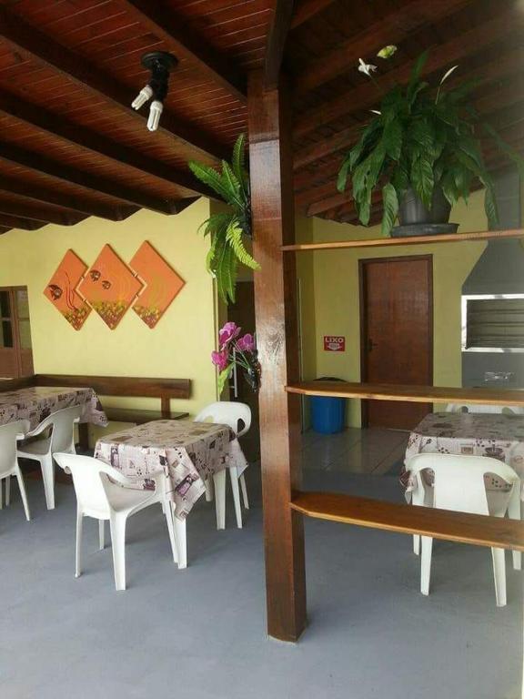 a room with tables and white chairs and a room with tables and tablesktop at Pousada garopaba in Garopaba