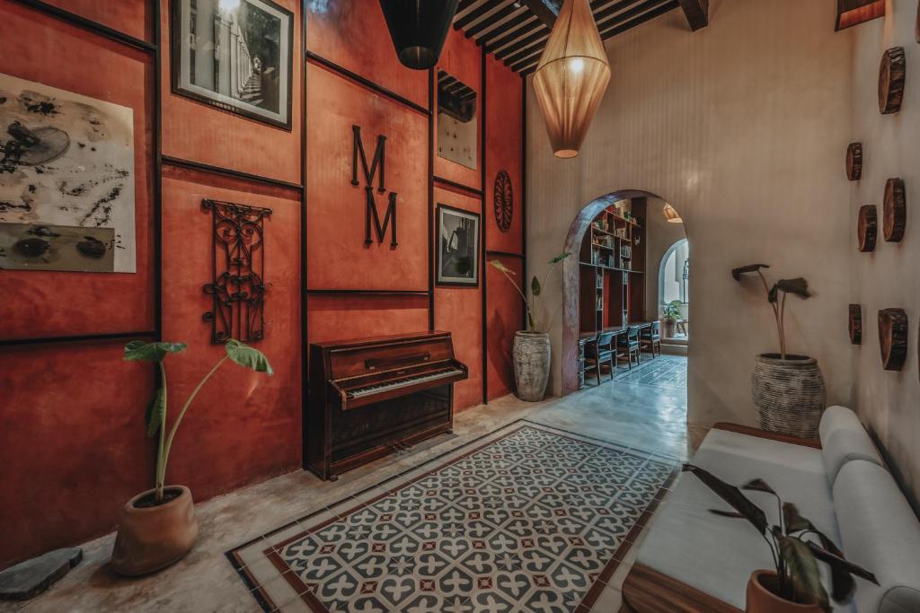a hallway with a piano in a room with red walls at MUR MURA Boutique Guesthouse in Campeche
