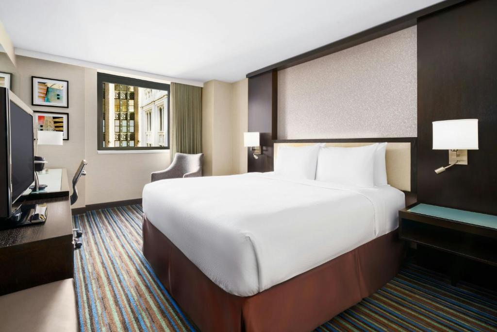 a hotel room with a large bed and a television at Courtyard New York Manhattan/Times Square in New York