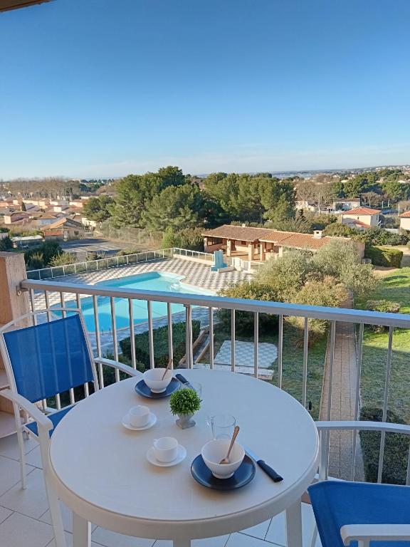 - une table sur un balcon avec vue sur la piscine dans l'établissement Chez Laurette, à Balaruc-les-Bains