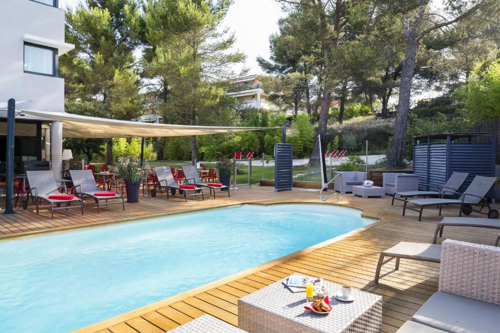 a large swimming pool with chairs and tables on a deck at Hôtel de l'Arbois in Aix-en-Provence