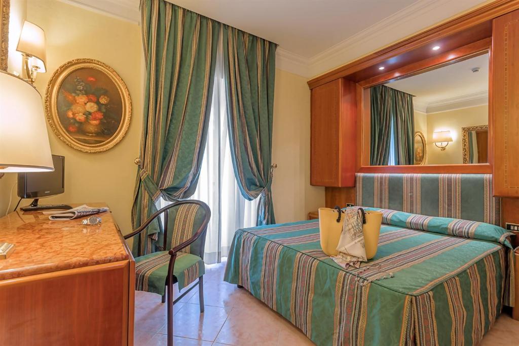 Pokój hotelowy z łóżkiem, biurkiem i lustrem w obiekcie Raeli Hotel Luce w Rzymie