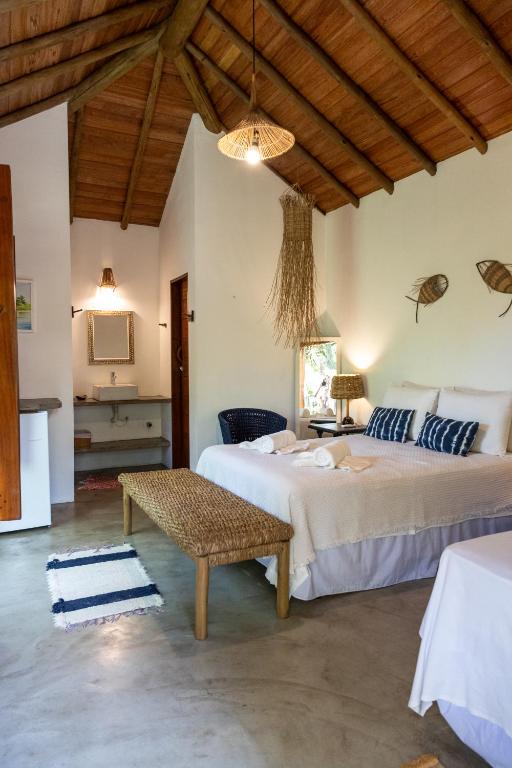 a bedroom with two beds and a table at Chalés Casulo Caraíva in Caraíva
