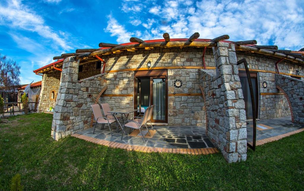una casa in pietra con due sedie e un tavolo di Theano Apartments a Sárti