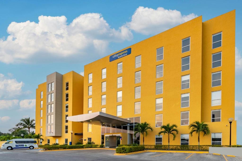 un hotel giallo con una macchina parcheggiata in un parcheggio di City Express by Marriott Tuxpan a Tuxpan de Rodríguez Cano