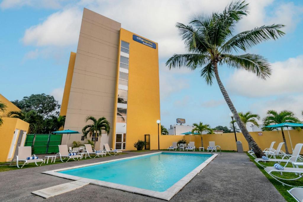 una piscina di fronte a un hotel con una palma di City Express by Marriott Tuxpan a Tuxpan de Rodríguez Cano