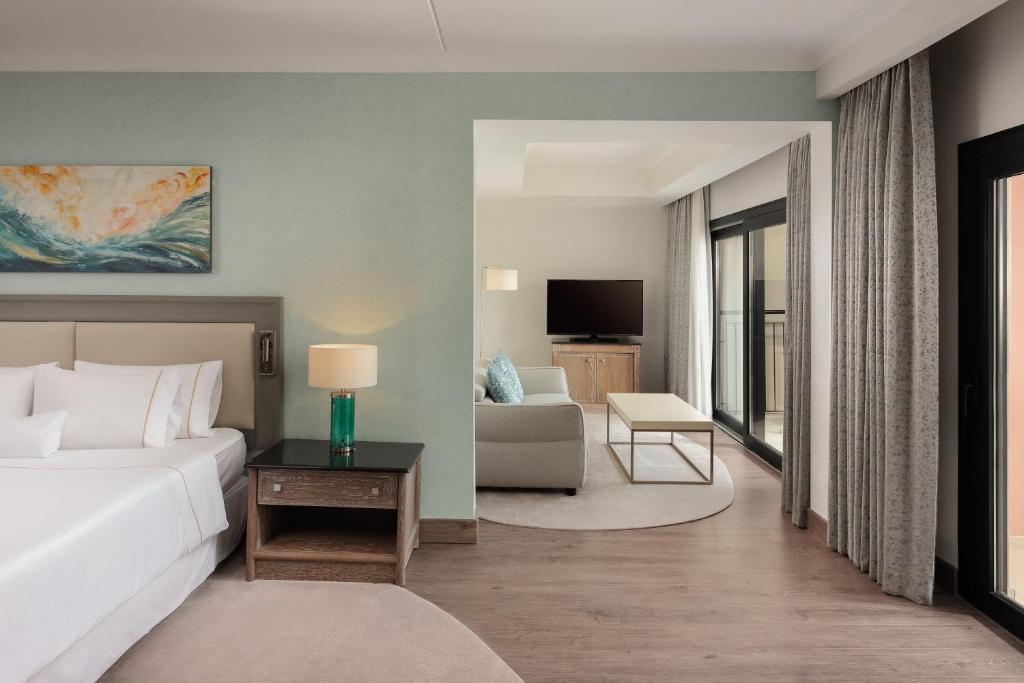 a bedroom with a bed and a living room at The Westin Dragonara Resort, Malta in St. Julianʼs