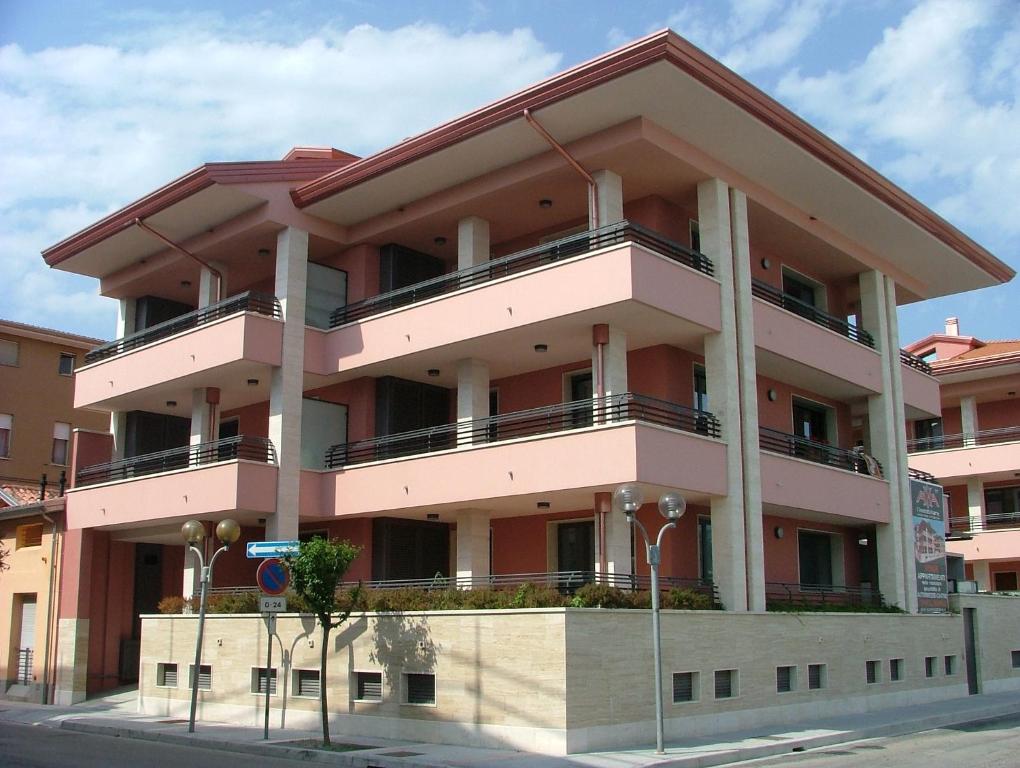 un bâtiment rose avec balcon dans une rue dans l'établissement Residence Magnolia, à Grado