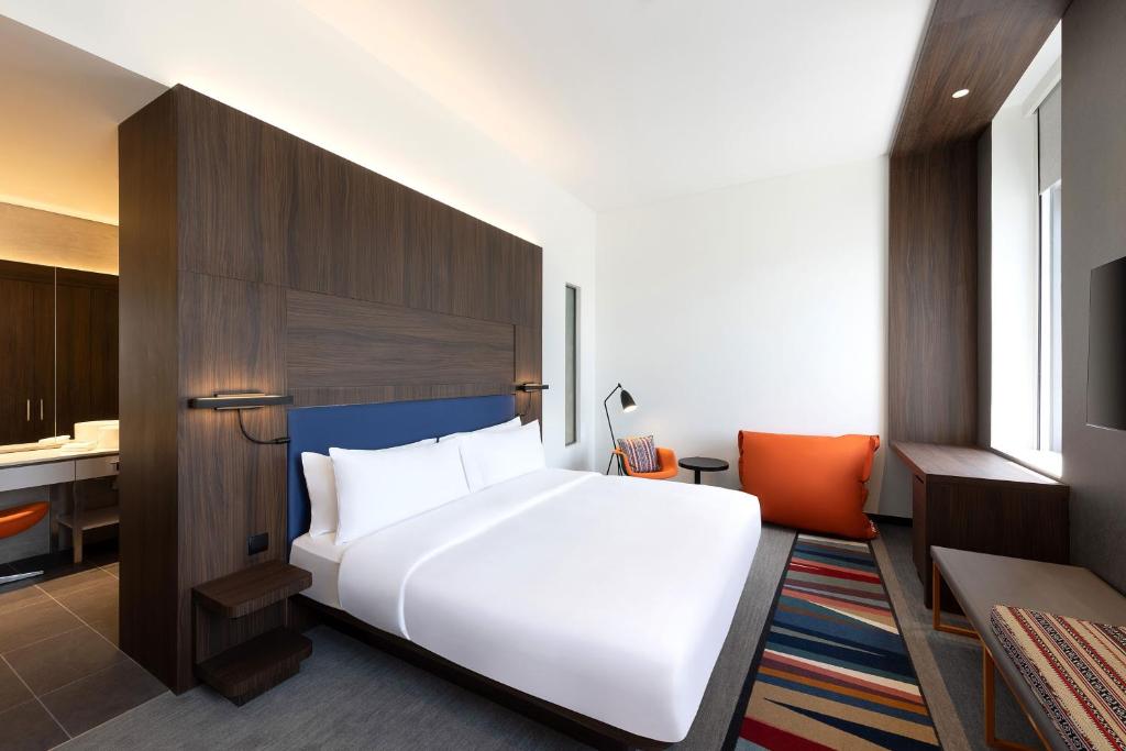 a bedroom with a large white bed and a kitchen at Aloft by Marriott Al Mina, Dubai in Dubai