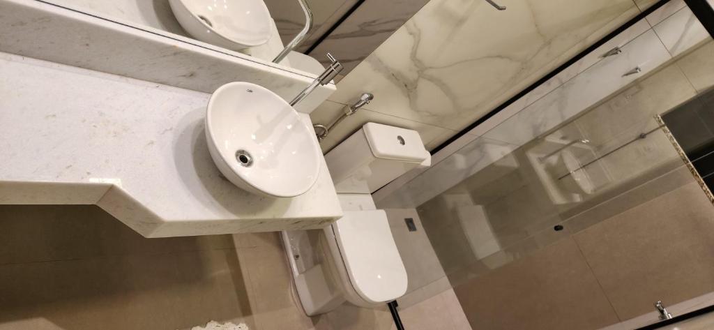 un bagno con lavandino, WC e specchio di Casa aconchegante e tranquila no centro da cidade a Passa Quatro