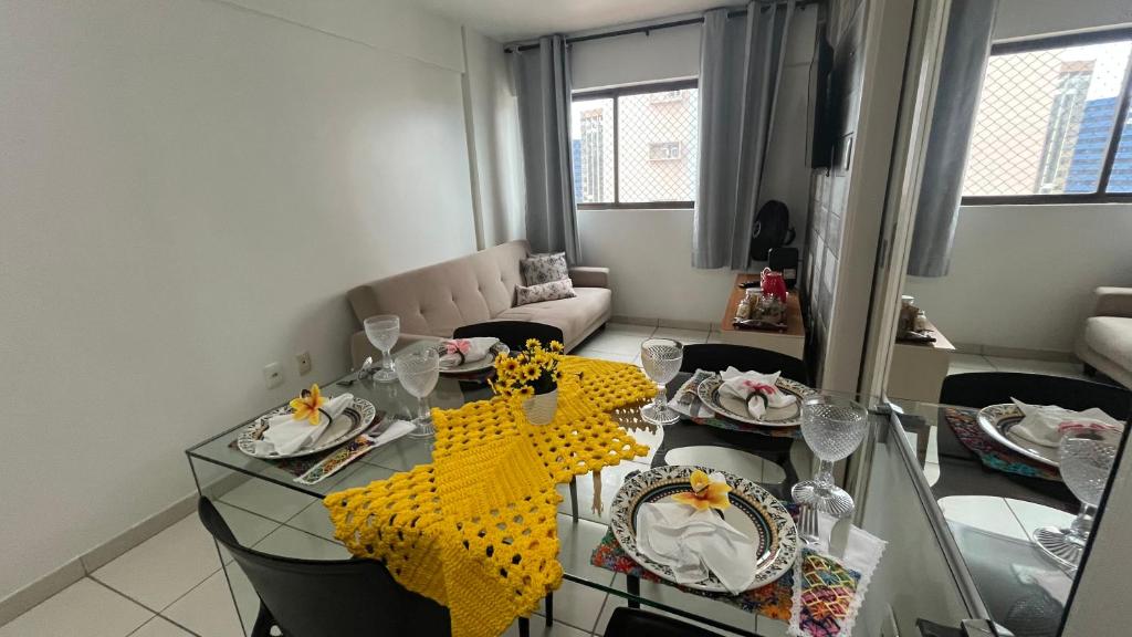 a living room with a glass table with yellow napkins at Gales de Pajuçara 703 Conforto, Piscina na Cobertura, Wifi 350 Mbps e a 50m da Praia! in Maceió